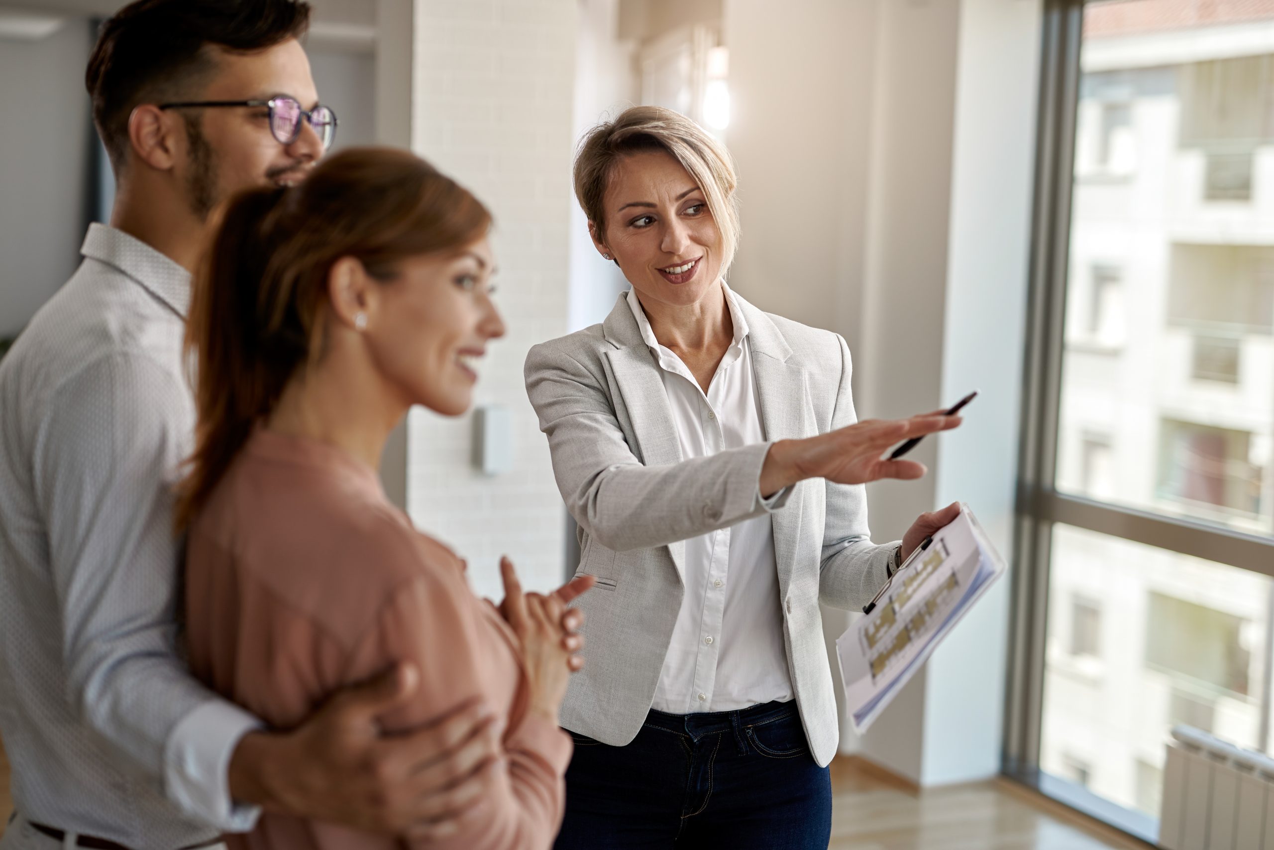 agente inmobiliario sonriente hablando con una pareja interesada en comprar una casa nueva scaled Actum Advocats Girona